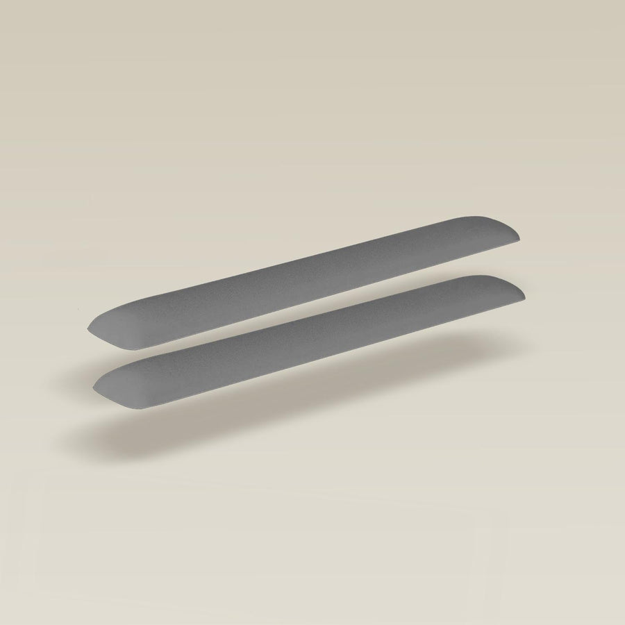 Two grey memory foam armrests for Ironside tables, with curved ends and a smooth texture.