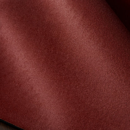 A close-up of a textured fabric material in a deep burgundy red color, showing the fine weave and soft folds.