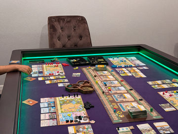 A board game set up on a dark table with a purple playmat